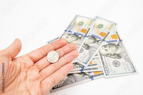 A hand holding one ruble coin and american dollar banknotes on background, ruble devaluation and usd-rub exchange rate concept