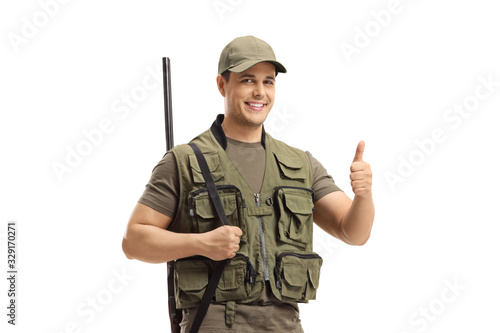 Young hunter with a shotgun on his shoulder showing thumbs up sign