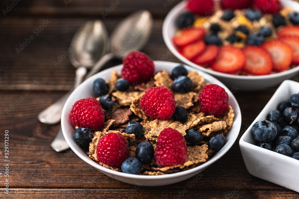 Granola with blueberries and raspberries in white bowl in dark wooden desk. Granola with blueberries and raspberries in white bowl in dark wooden desk.