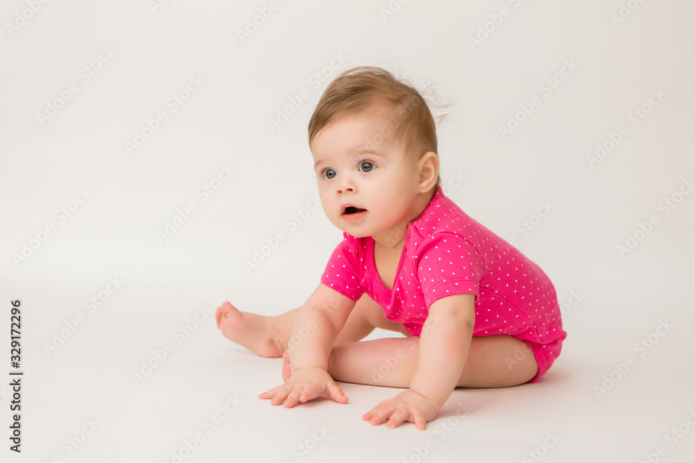 healthy baby girl in a pink bodysuit sits on a white background. space for text healthy baby girl in a pink bodysuit sits on a white background. space for text