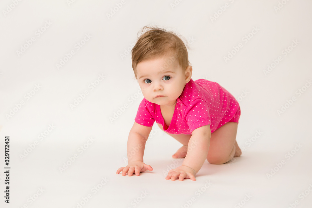 healthy baby girl in a pink bodysuit sits on a white background. space for text healthy baby girl in a pink bodysuit sits on a white background. space for text