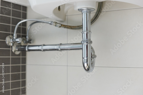 metal sink siphon and drain in white bathroom
