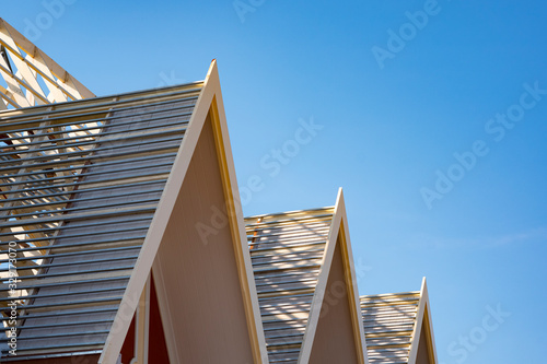 Low angle and side view of 3 wooden gable roofs structure under construction against blue sky background, renovation and improvement in home exterior concept