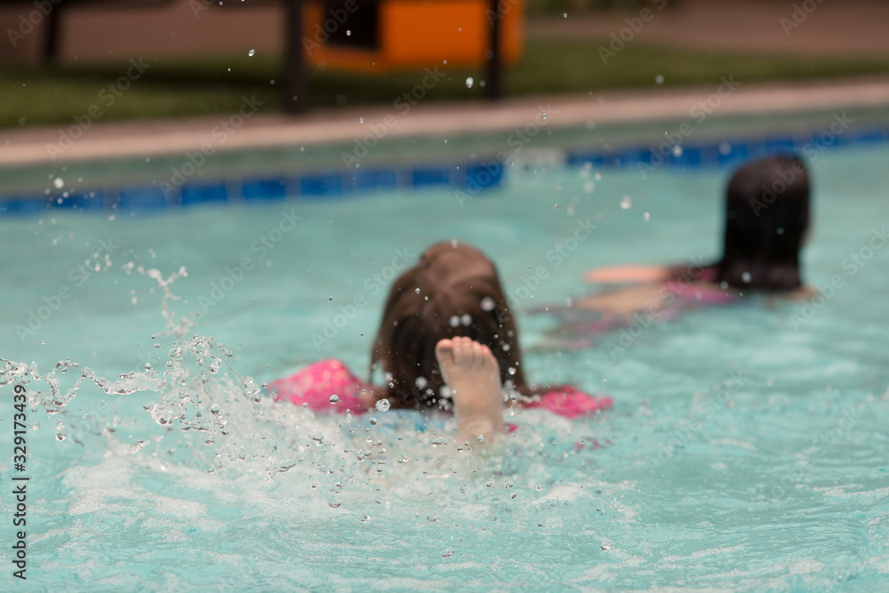 Kids are swimming in a pool on a hot summer day.