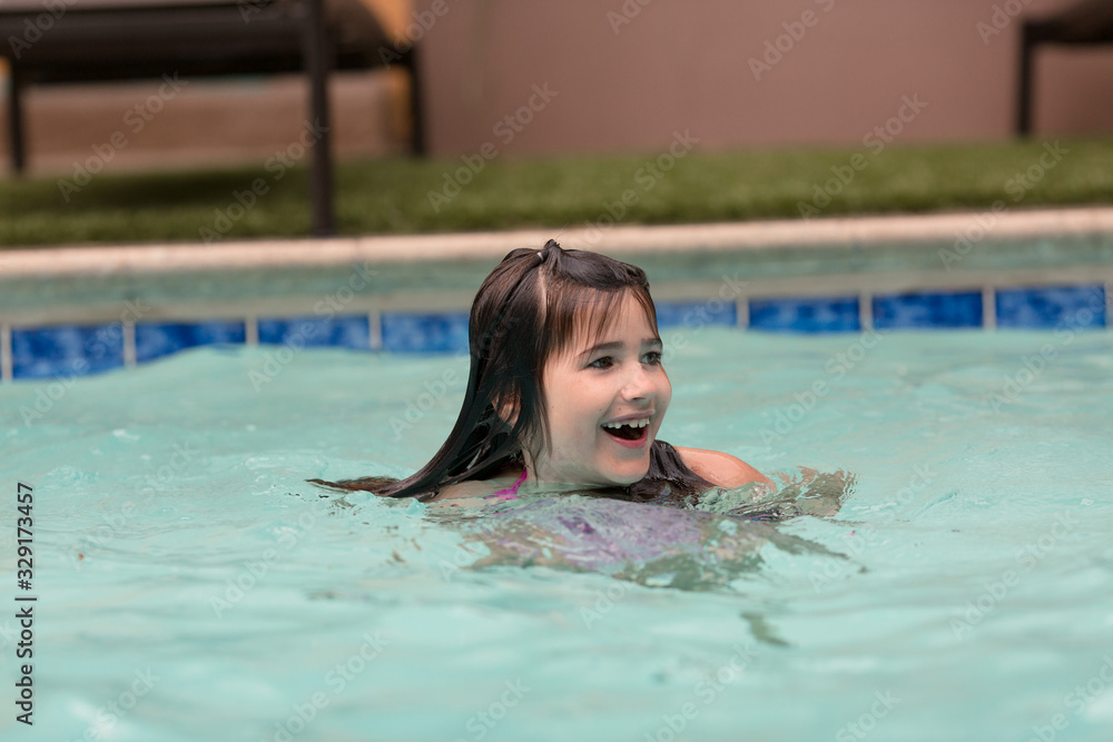 Kids are swimming in a pool on a hot summer day.
