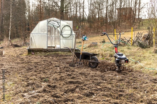  Agricultural work. Gardening. Spring preparation soil for seeding with tiller.  Spade, pitchfork and rake. Life on a small farm. photo