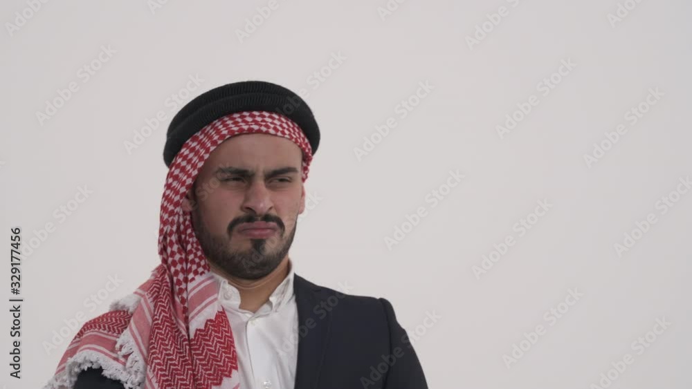 Young Arab man nods his head slightly and then looks at the camera. Disapproval, no gesture. Isolated, on white background Young Arab man nods his head slightly and then looks at the camera. Disapproval, no gesture. Isolated, on white background
