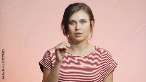 young woman checking result of a medical pregnancy test, girl looking with big scared eyes, female emotions on a colored studio background photo