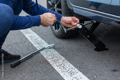 Man is jacking up broken car, wheel replacement. Tire replacement concept.