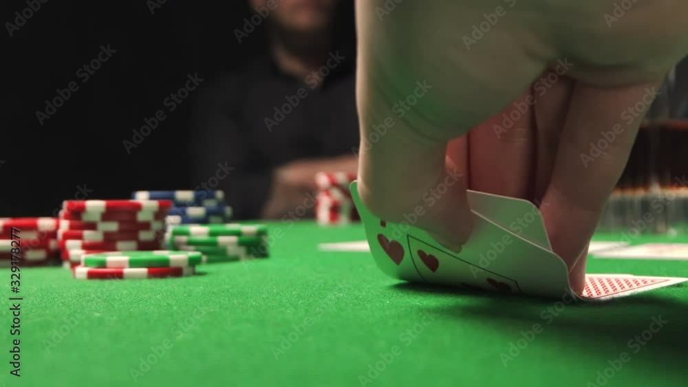 Woman playing poker, checking her hand, holding a pair of cards. Woman vs man. Woman playing poker, checking her hand, holding a pair of cards. Woman vs man.