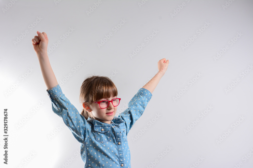 Young beautiful happy girl portrait isolated on gray. Young smiling girl holding hands up, looking at camera. Young beautiful happy girl portrait isolated on gray. Young smiling girl holding hands up, looking at camera.