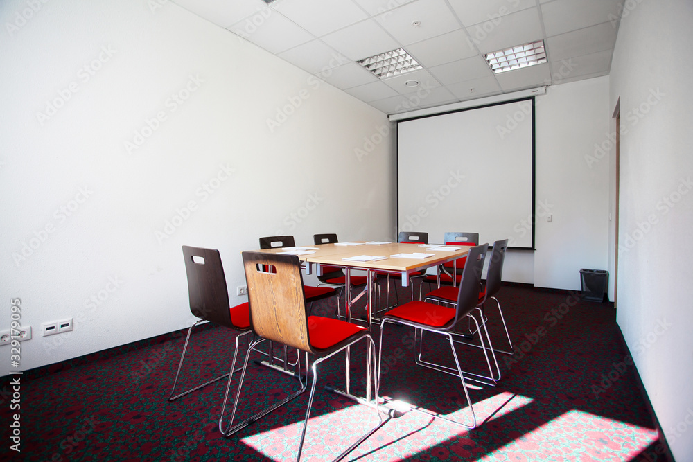 Interior of empty modern meetingroom. Conference room in a hotel for business training. Rows of chairs and desks. Boardroom with presentation screen and projector... Interior of empty modern meetingroom. Conference room in a hotel for business training. Rows of chairs and desks. Boardroom with presentation screen and projector...