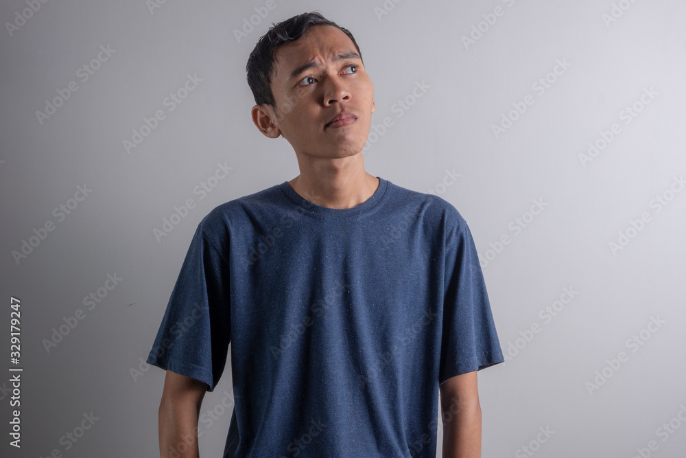 a Young Asian man who is confused thinking about something a Young Asian man who is confused thinking about something