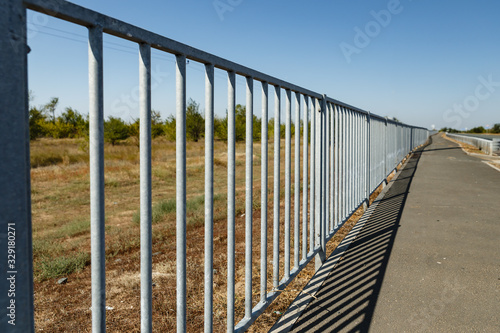 metal fence between the field and the pedestrian walkway on the highway.