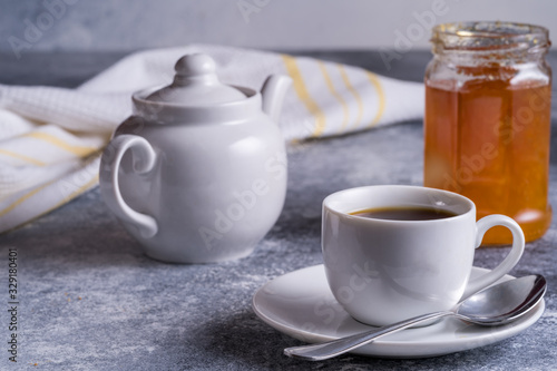 Cup of tea, teapot and jam on a table, blurred bokeh background.