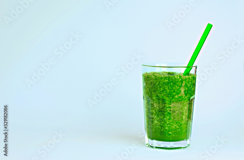 Green detox smoothie with vegetables on blue background. Healthy drink.