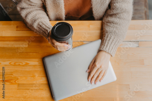 The girl works at the computer and drinks coffee photo