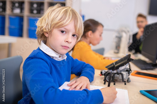 Boy and girl sitting at desk, taking notes