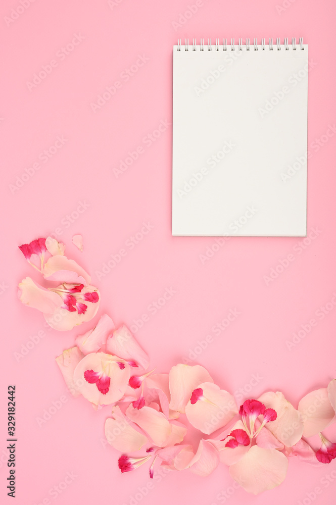 Styled flat lay mockup with floral elements on pink table. Copy space.