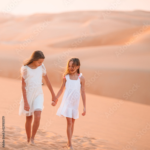 Girls among dunes in big desert in Emirates