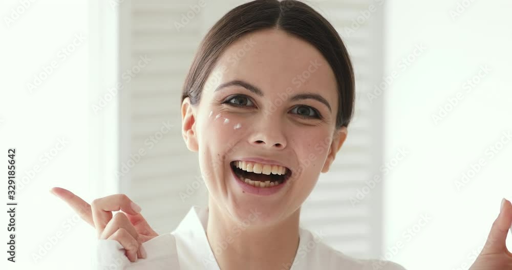Happy pretty young woman holds creme jar covers eye looking at camera. Playful teen girl pointing finger at copy space advertising facial skin care cream. Skincare treatment concept, close up portrait Happy pretty young woman holds creme jar covers eye looking at camera. Playful teen girl pointing finger at copy space advertising facial skin care cream. Skincare treatment concept, close up portrait