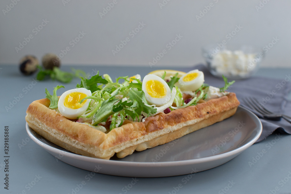 Belgian waffles with boiled quail eggs, mix of green leaves and cheese.
