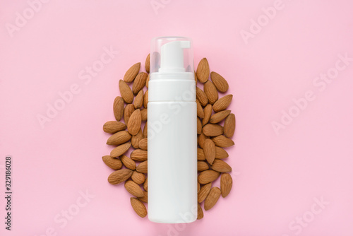 Body lotion enriched with vitamins organic minerals concept. Top above overhead flatlay flat lay photo of bottle with almond nuts isolated pastel color empty background