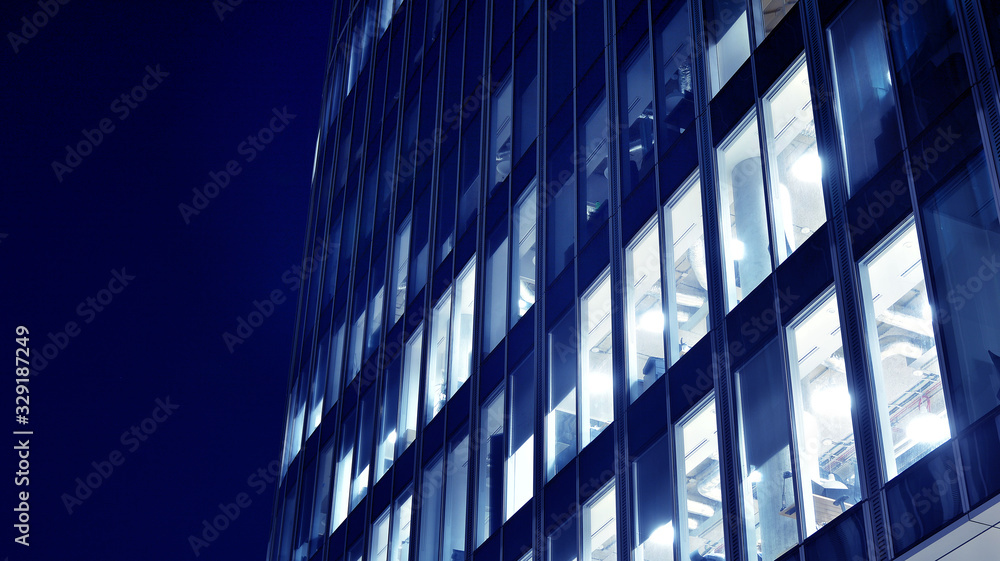 Night architecture - building with glass facade.Blue color of night lights. Modern building in business district. Concept of economics, financial. Photo of commercial office building exterior. Abstra Night architecture - building with glass facade.Blue color of night lights. Modern building in business district. Concept of economics, financial. Photo of commercial office building exterior. Abstra