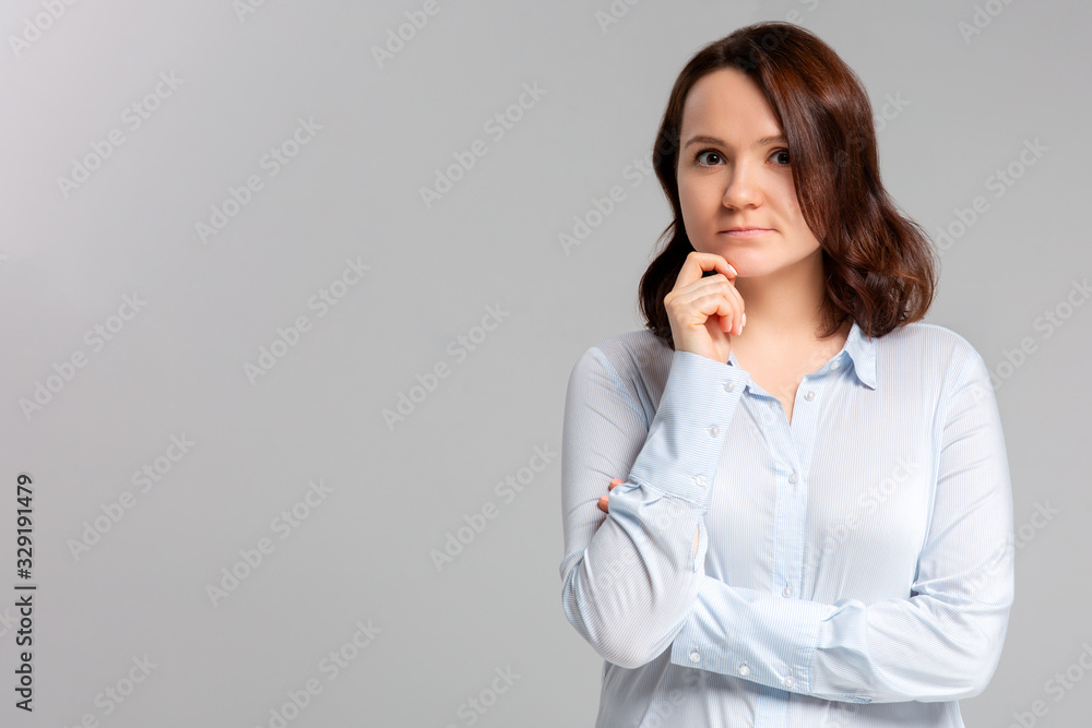 Portrait of beautiful casually dressed young Caucasian woman having doubtful expression, looking away cunningly in indecisiveness, holding her chin,trying to find best solution. Body language concept. Portrait of beautiful casually dressed young Caucasian woman having doubtful expression, looking away cunningly in indecisiveness, holding her chin,trying to find best solution. Body language concept.