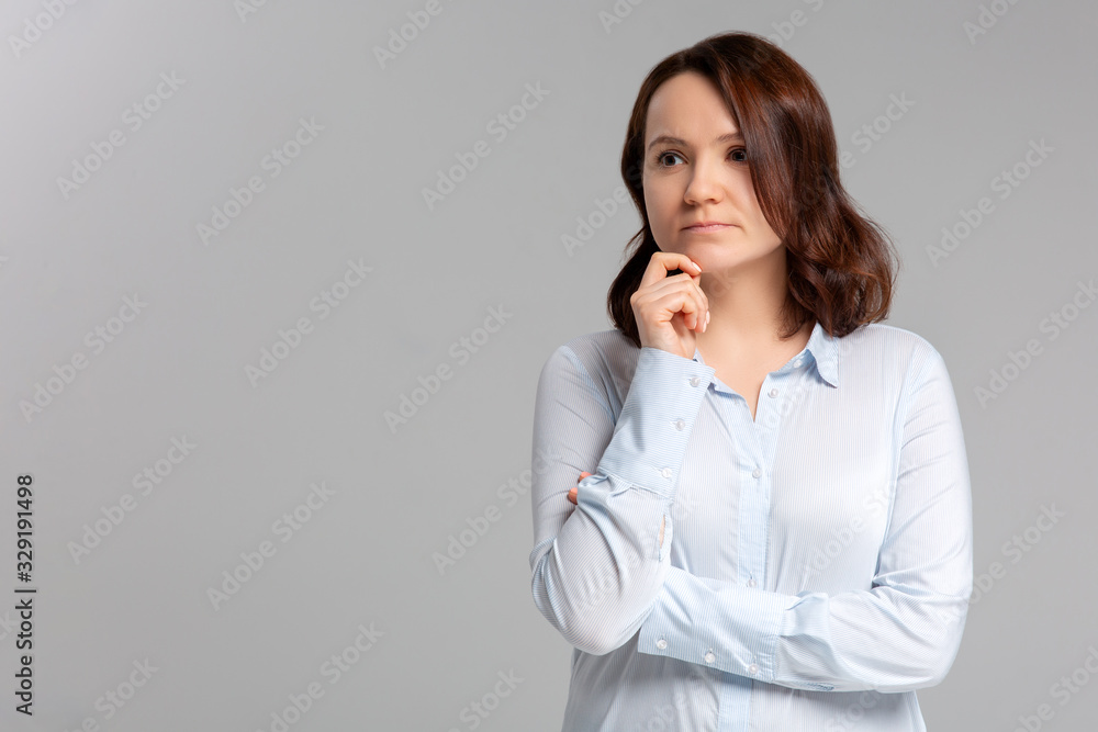 Portrait of beautiful casually dressed young Caucasian woman having doubtful expression, looking away cunningly in indecisiveness, holding her chin,trying to find best solution. Body language concept. Portrait of beautiful casually dressed young Caucasian woman having doubtful expression, looking away cunningly in indecisiveness, holding her chin,trying to find best solution. Body language concept.