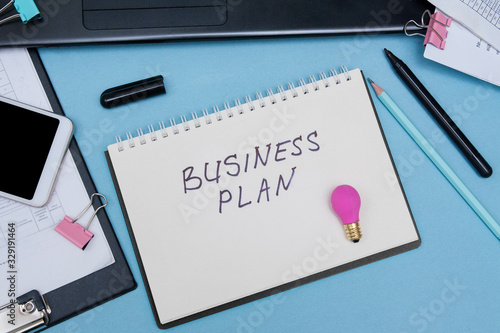 Woman workplace with notepad business plan. Top view on a blue background