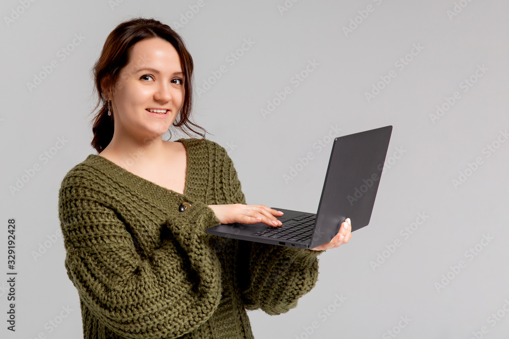 Charming young woman working freelance, remote from office, hold laptop, typing university essay, turn left smiling copy space, stand gray background joyful, browsing web using computer Charming young woman working freelance, remote from office, hold laptop, typing university essay, turn left smiling copy space, stand gray background joyful, browsing web using computer