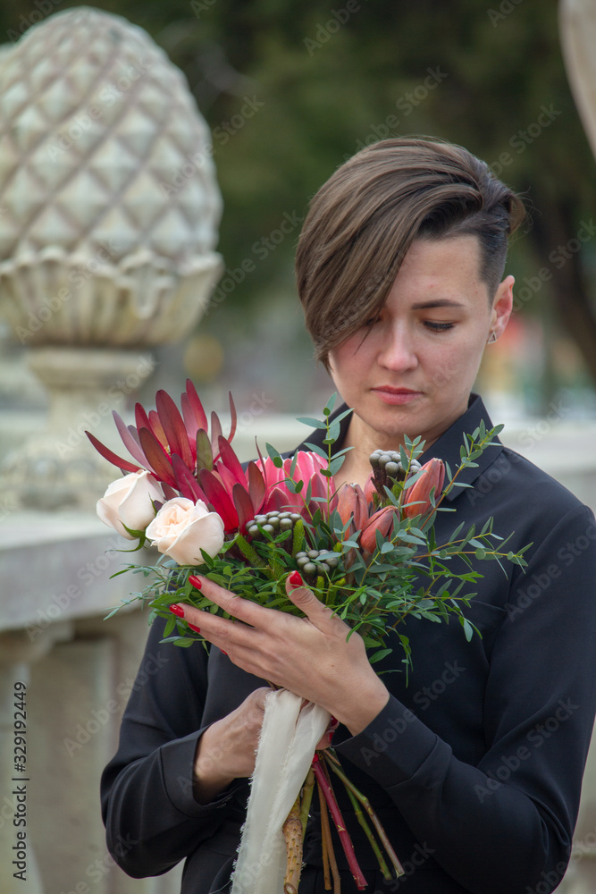 Fototapeta premium Dark-haired girl with a bouquet of flowers in a spring park, greeting concept