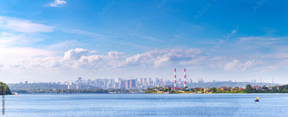Summer sunny hot evening. Modern residential areas southern suburbs and midtown on hills in Kyiv on the right bank of the Dnipro River. Fishermen on boats on foreground. Kyiv. Ukraine. Aug. 28, 2019 Summer sunny hot evening. Modern residential areas southern suburbs and midtown on hills in Kyiv on the right bank of the Dnipro River. Fishermen on boats on foreground. Kyiv. Ukraine. Aug. 28, 2019