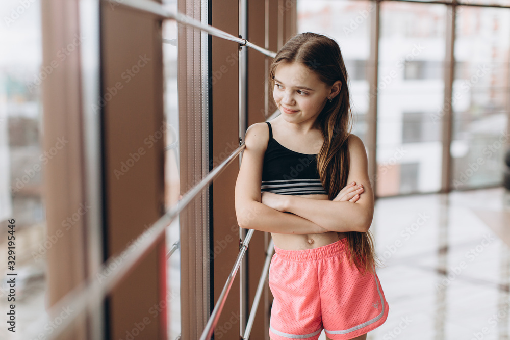 Charming little girl looking the window after yoga exercises in fitness hall