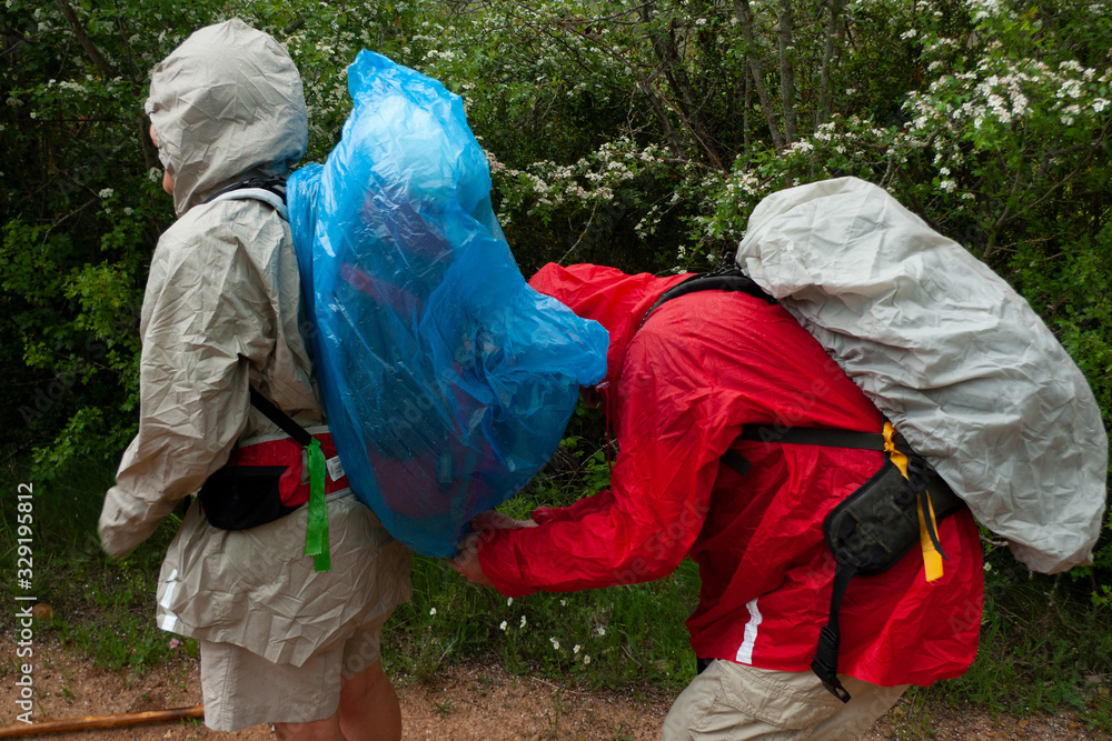 Pareja de peregrinos del Camino de Santiago colocándose el cubre mochilas en medio de una tormenta. Pareja de peregrinos del Camino de Santiago colocándose el cubre mochilas en medio de una tormenta.