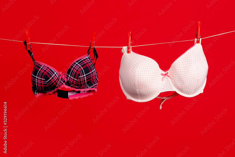 Breast size. Big and small breasts. Brassiere. Women's lingerie hanging at  rope . Bra and bustiers. Small little or big breast size. Stock Photo
