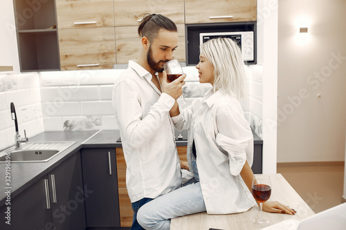 Cute couple in a kitchen. Lady in a white t-shirt. Pair at home drinking a vine.