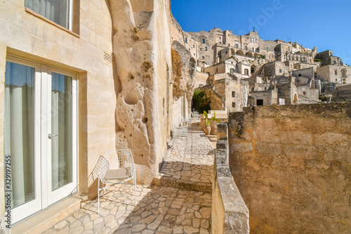 A modern sliding glass door and metal chair sit outside a patio in the ancient cave hillside city of Matera, Italy.