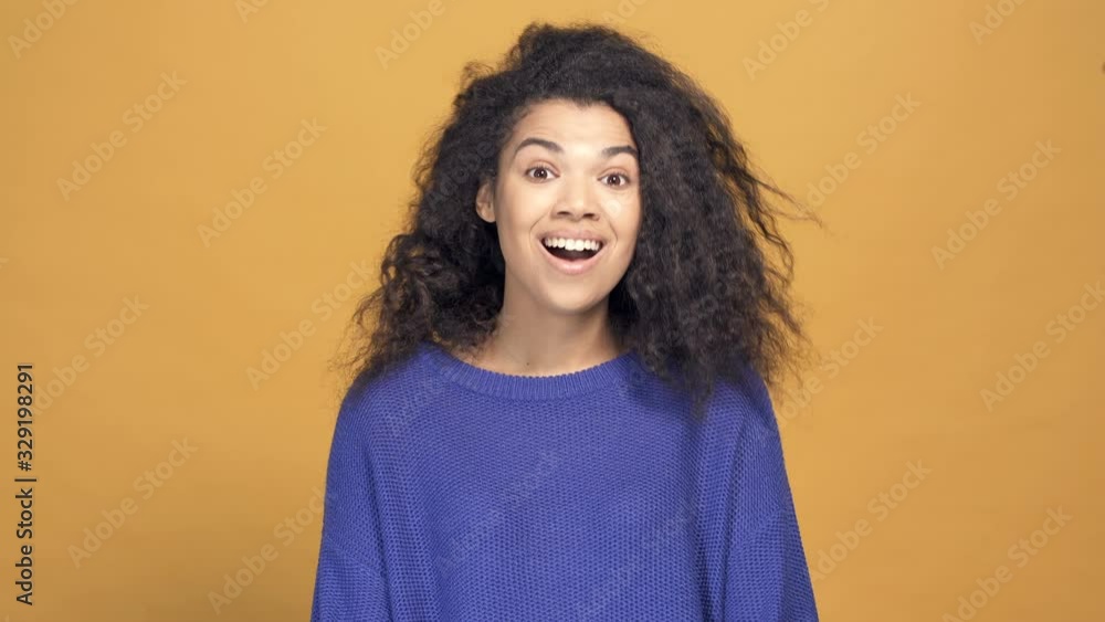 Portrait of wonder and surprised afro american woman showing thumbs up sign. Smiling and looking at the camera. Yellow background. Portrait of wonder and surprised afro american woman showing thumbs up sign. Smiling and looking at the camera. Yellow background.