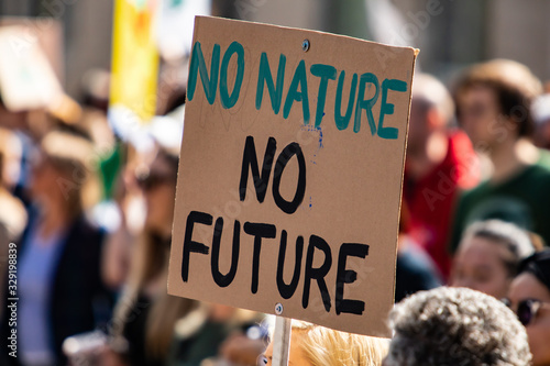 A simple and effective climate change poster is seen during a city rally, saying no nature no future, with blurry protestors in background and copy space