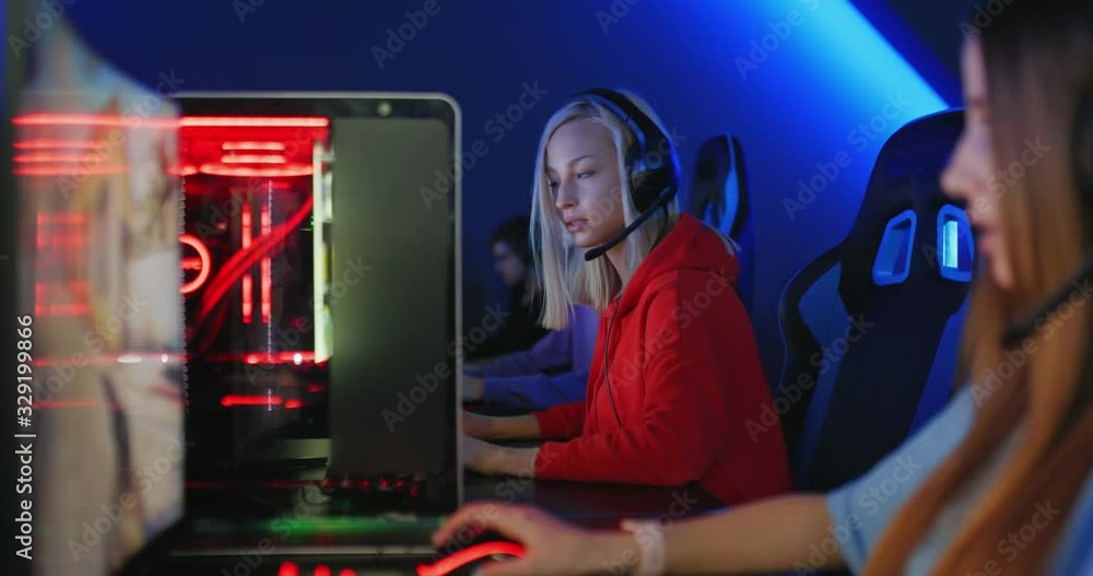 Beautiful young women are sitting at computers with headphones in a computer club, team game online. Computer club with good equipment and modern technology. Cybersport. Beautiful young women are sitting at computers with headphones in a computer club, team game online. Computer club with good equipment and modern technology. Cybersport.