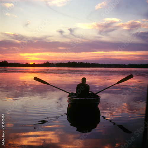 Silhouette of man peacefully rowing boat at sunset. Lake Kegonsa Wisconsin WI USA