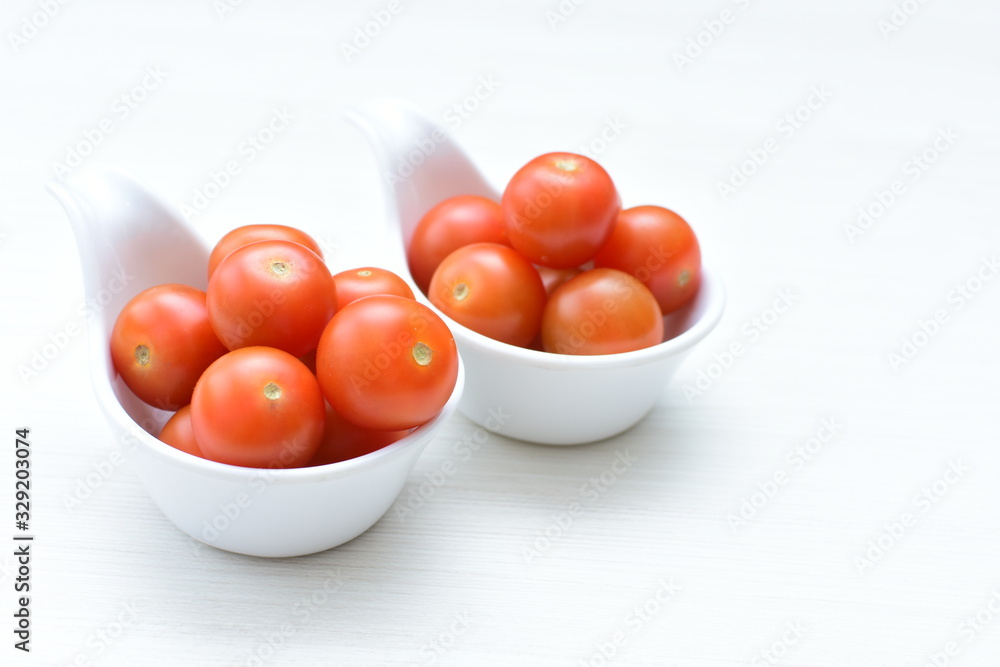 Fresh cherry tomato, displayed in containers on white wooden background Fresh cherry tomato, displayed in containers on white wooden background