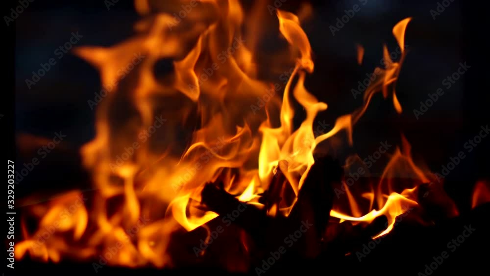 Fire flames and a lot of bright sparks are flying from the fire at black background Fire flames and a lot of bright sparks are flying from the fire at black background