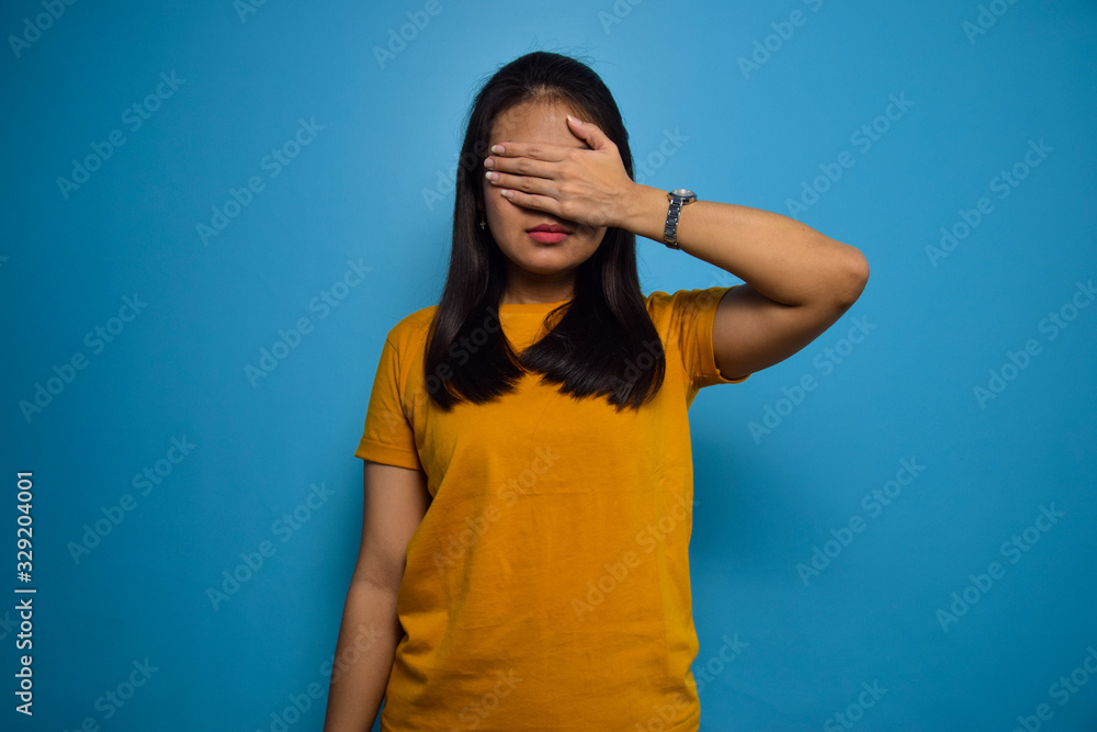 Portrait of Young beautiful asian women with blue isolated background, covering eyes gesture Portrait of Young beautiful asian women with blue isolated background, covering eyes gesture