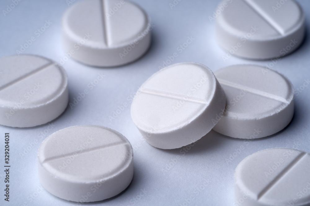 Closeup of white pills on a white background with texture. Closeup of white pills on a white background with texture.