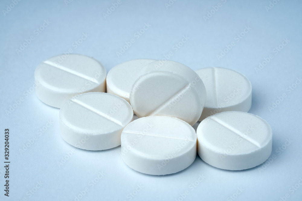 Closeup of white pills on a white background with texture. Closeup of white pills on a white background with texture.