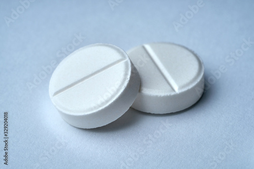 Closeup of two white tablets on a white background with texture.