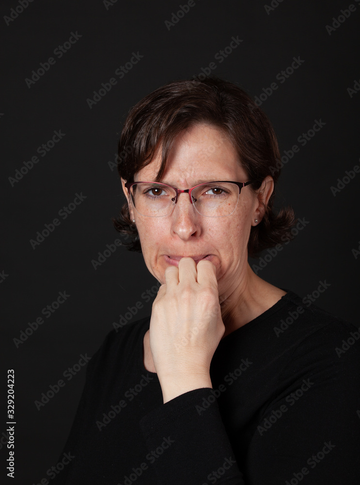 Woman in black with hand to mouth wearing glasses Woman in black with hand to mouth wearing glasses